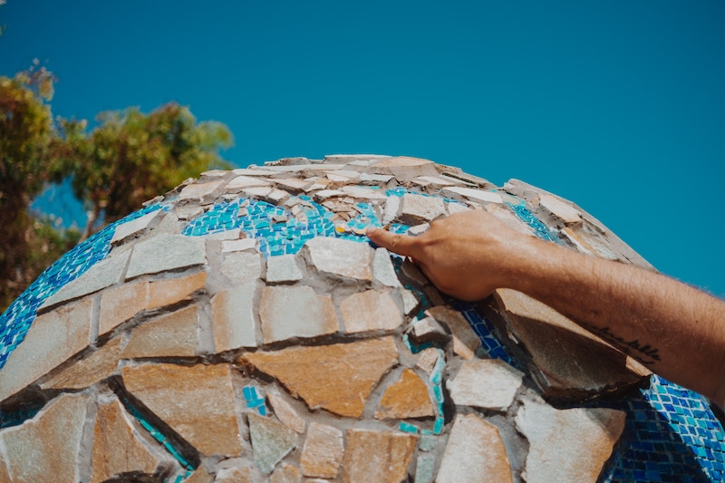 Hand touching a globe made of rocks
